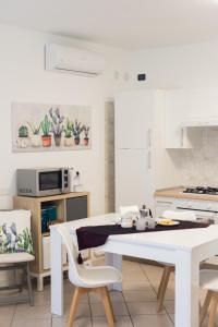 een witte keuken met een witte tafel en stoelen bij Flor Thermae&Relax in Montegrotto Terme