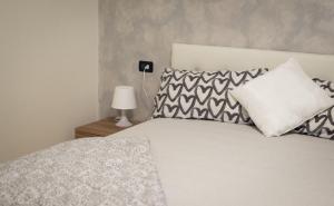 een slaapkamer met een wit bed met kussens en een lamp bij Flor Thermae&Relax in Montegrotto Terme