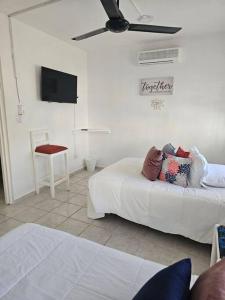 Schlafzimmer mit einem Bett, einem TV und einem Stuhl in der Unterkunft Hermosa Suites #9 in the heart of PUNTA CANA in Punta Cana