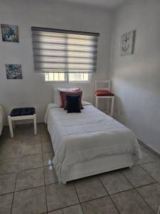 ein Schlafzimmer mit einem weißen Bett und einem Fenster in der Unterkunft Hermosa Suites #9 in the heart of PUNTA CANA in Punta Cana