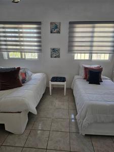 2 Betten in einem Zimmer mit 2 Fenstern in der Unterkunft Hermosa Suites #9 in the heart of PUNTA CANA in Punta Cana