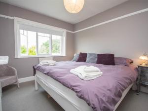 a bedroom with a bed with purple sheets and a window at 3 Bed in Studland DC071 in Studland