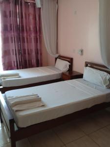 twee bedden in een kleine kamer met een raam bij Checkpoint Inn Hotel, Mombasa in Mombasa
