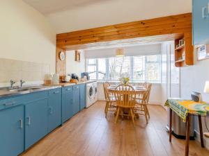 a kitchen with blue cabinets and a table with chairs at 3 bed in Kirriemuir 82244 in Kirriemuir