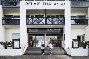two people walking up the stairs in front of a building at Hotel & Spa 4* Serge Blanco in Hendaye