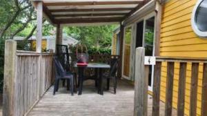 une terrasse en bois avec une table et des chaises sur une maison dans l'établissement Charmant mobilhome 4 pers, à Biscarrosse
