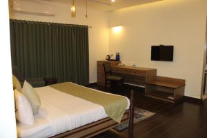 - une chambre avec un lit, un bureau et une télévision dans l'établissement WelcomHeritage Tadoba Vanya Villas Resort & Spa, à Kolāra