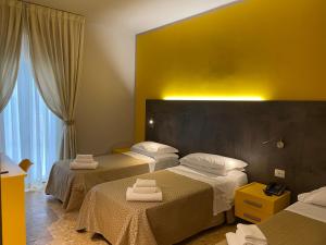 una camera d'albergo con tre letti e asciugamani di Hotel Lukas a Viareggio