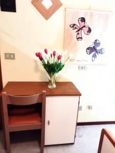 una mesa con un jarrón de flores encima en Hotel Ambasciata, en Cesenatico