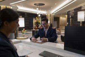 un hombre sentado en un escritorio escribiendo en un pedazo de papel en Crowne Plaza Bangkok Lumpini Park, an IHG Hotel en Bangkok