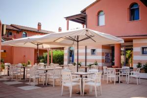 un patio esterno con tavoli, sedie e ombrelloni di Residenza dei Cavalleggeri a San Vincenzo