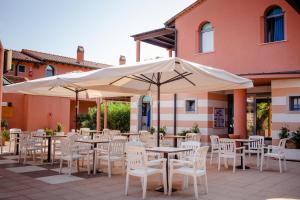 an outdoor patio with tables and chairs and umbrellas at Residenza dei Cavalleggeri in San Vincenzo