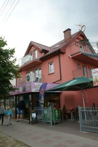 a pink building with people walking in front of it at OWR Grażyna in Międzywodzie