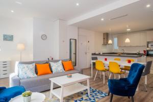 Brand New Stylish Apartment with Fluffy Beds 1 في فالنسيا: غرفة معيشة ومطبخ مع أريكة وكراسي