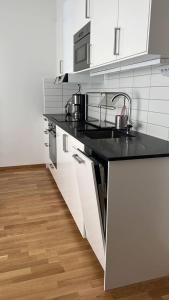 a kitchen with a black counter top and white cabinets at Private Terrace Apartment in Gothenburg