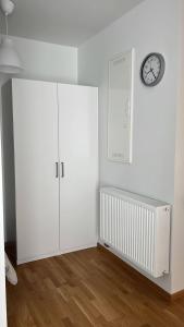 une chambre blanche avec une armoire blanche et une horloge dans l'établissement Private Terrace Apartment, à Göteborg