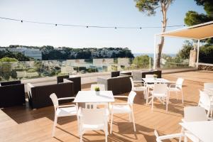 a restaurant with white tables and chairs on a deck at Comitas Floramar in Cala Galdana