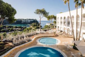 vistas a la piscina de un complejo con sillas y un edificio en Comitas Floramar, en Cala Galdana