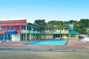 a large building with a swimming pool in front of it at Gunners Club in Minneriya