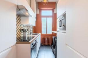 a kitchen with orange walls and white cabinets at Charming and comfortable apartment near tramway in Marcq-en-Baroeul