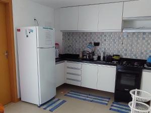 a kitchen with white cabinets and a white refrigerator at Vilage Aconchegante - Imbassaí in Imbassai