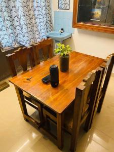 una mesa de madera con sillas y una maceta. en Vibes of Varkala Homestay, en Varkala