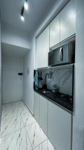 a kitchen with white cabinets and a microwave at Loft Moderno e Charmoso em Teresópolis - Alto in Teresópolis