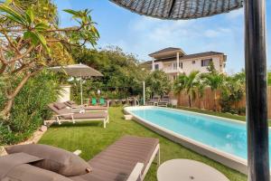 Un patio trasero con piscina y una casa. en Windsock Apartment Kas Salty, en Kralendijk
