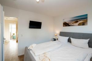 1 dormitorio con 1 cama grande con sábanas blancas en Alea, en Westerland