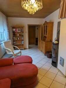 a living room with a red couch and a chandelier at Ferienhaus Brigitte in Dichtelbach