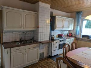 a kitchen with white cabinets and a table and a sink at Ferienhaus Brigitte in Dichtelbach