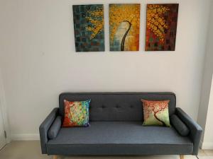ein Sofa in einem Zimmer mit drei Gemälden an der Wand in der Unterkunft Annex D. One Bedroom flat in south London in Carshalton