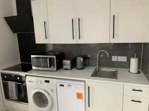 a kitchen with a microwave and a washer and a sink at Annex D. One Bedroom flat in south London in Carshalton