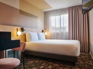 a hotel room with a large bed and a window at Mercure Paris 15 Porte de Versailles in Paris