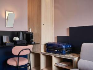 パリにあるメルキュール パリ 15 ポルト ドゥ ベルサイユのデスク、スーツケース、椅子が備わる客室です。