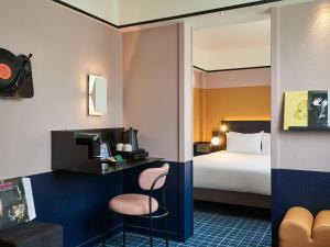 パリにあるメルキュール パリ 15 ポルト ドゥ ベルサイユのベッド、デスク、椅子が備わるホテルルームです。