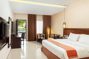 a hotel room with a large bed and a television at Best Western Resort Kuta in Kuta
