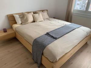 Sonniges und stylishes Bijou in St. Moritz Bad في سان موريتز: سرير كبير مع اطار خشبي في غرفة النوم