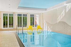 ein Pool mit zwei gelben Stühlen in einem Gebäude in der Unterkunft Dünenschloss Dünenschloss 2-09 in Kühlungsborn