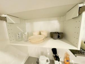 a white kitchen with plates and dishes on a shelf at 山手線恵比寿8分　4人可　 in Tokyo