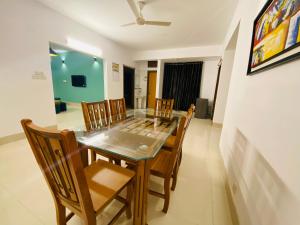 a dining room with a glass table and wooden chairs at Amazing Apartment in Bashundhara in Dhaka
