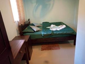 a small bed with a green comforter in a room at Chalisa Bukit House Lanta in Ban Mo Nae