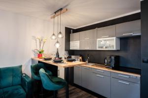 una cocina con encimera y algunas sillas verdes en Apartament w Winiarni, en Dąbrówka Szczepanowska