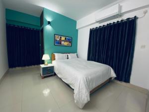 a bedroom with a bed and a blue wall at Amazing Apartment in Bashundhara in Dhaka