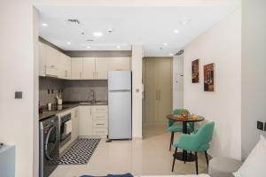 cocina con armarios blancos, mesa y sillas en Iolanda Home, en Dubái