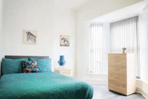 a bedroom with a green bed and a wooden dresser at Bright 4BR Home, Perfect for Groups in Liverpool
