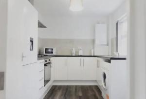 a white kitchen with white cabinets and a sink at Bright 4BR Home, Perfect for Groups in Liverpool