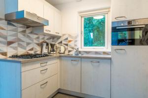 a kitchen with white cabinets and a sink and a window at Nieuwlanderweg 51 in De Waal