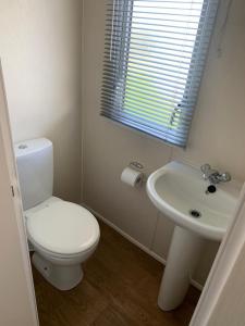 a white bathroom with a toilet and a sink at McCanns Caravan Marton Mere in Blackpool