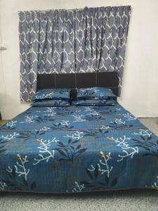 a bed with a blue comforter and a head board at Comfort Stay Kuala Perlis Wi-Fi Nexflix in Kuala Perlis